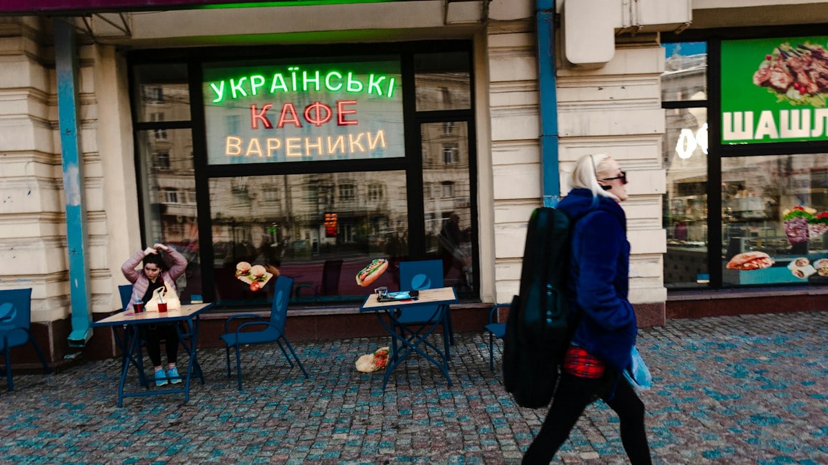 man in blue jacket walking on sidewalk during daytime